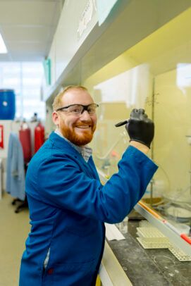 Person in a lab coat standing in a lab.