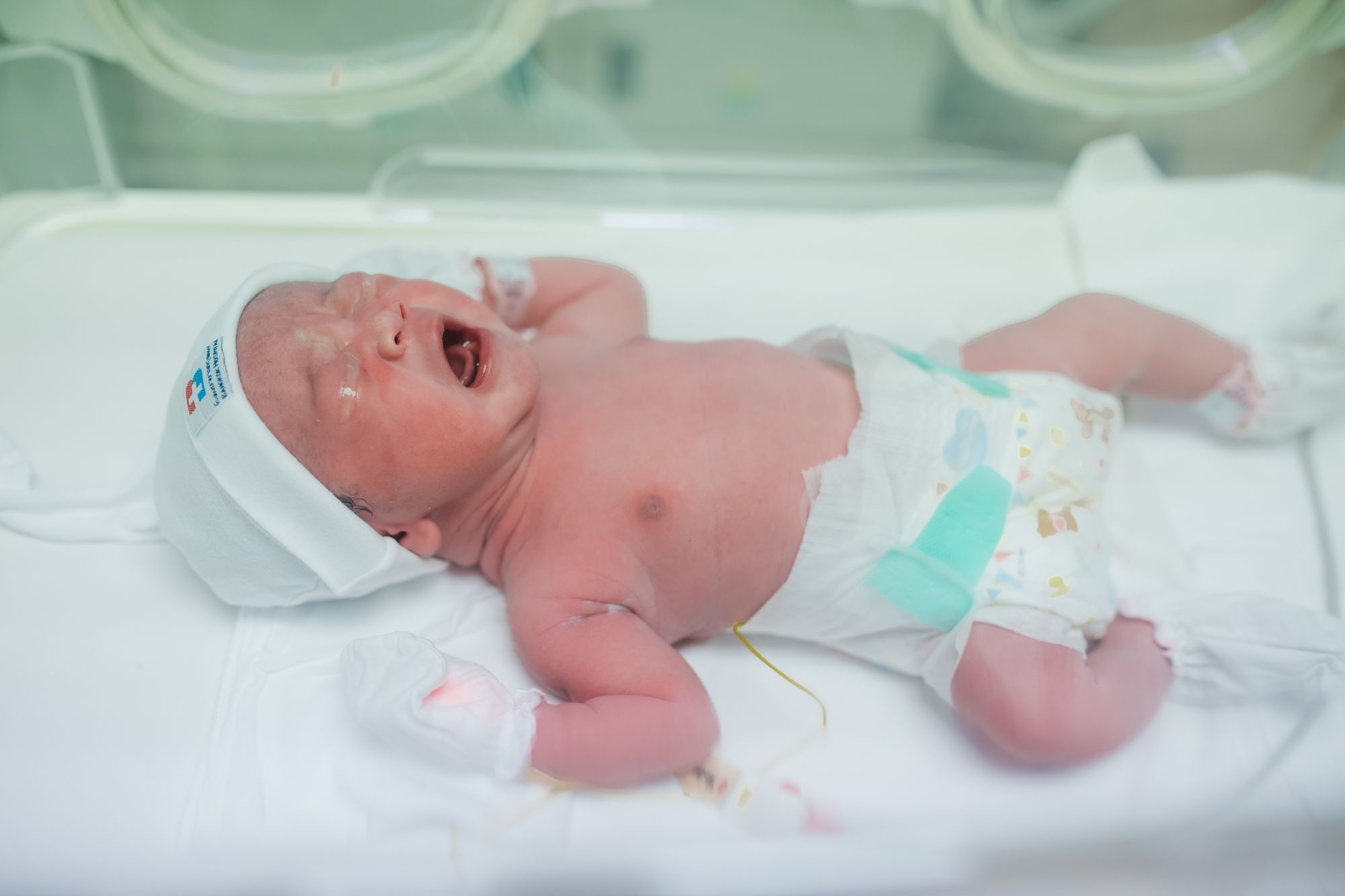 Infant crying in a hospital bassinet.